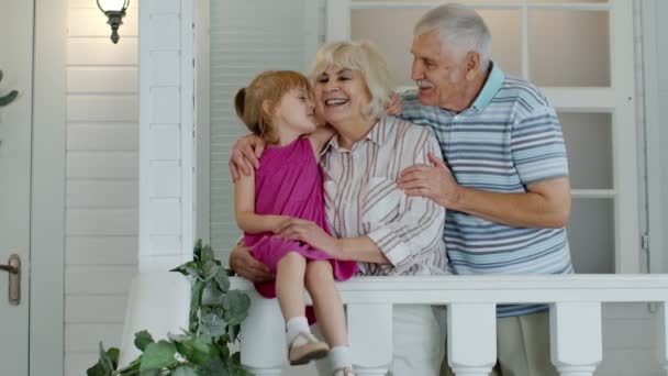Abuelo mayor y niña abrazando a la abuela y haciendo un beso en el porche en casa — Vídeos de Stock