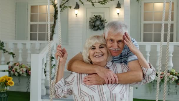 Seniorenpaar zusammen im Vorgarten zu Hause. Mann schwingt Frau und umarmt sie. Glückliche reife Familie — Stockvideo