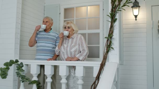 Mayores de edad pareja caucásica tomando café, abrazándose en el porche en casa. Maduro feliz familia — Vídeos de Stock