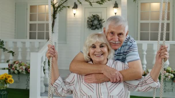 Pareja de ancianos juntos en el patio delantero en casa. Hombre balanceándose mujer durante cuarentena del Coronavirus — Vídeos de Stock