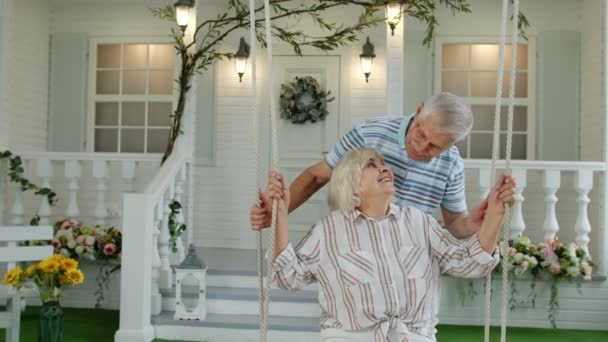 Casal sênior juntos no jardim da frente em casa. Homem balançando mulher durante quarentena Coronavirus — Vídeo de Stock