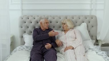 Yatakta pijamalı yaşlı bir çift yatak odasında tartışıyor. Büyükanne ve büyükbaba kavga eder.