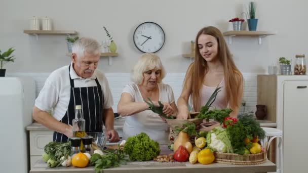 Casal sênior na cozinha que recebe verduras da neta. Nutrição saudável dos alimentos crus — Vídeo de Stock