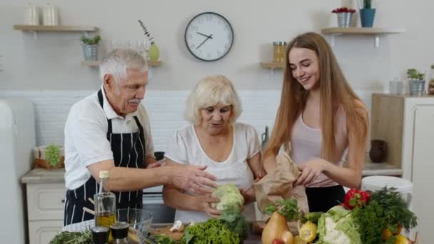 Couple âgé dans la cuisine recevant des légumes de petit-enfant. Alimentation crue saine alimentation — Video