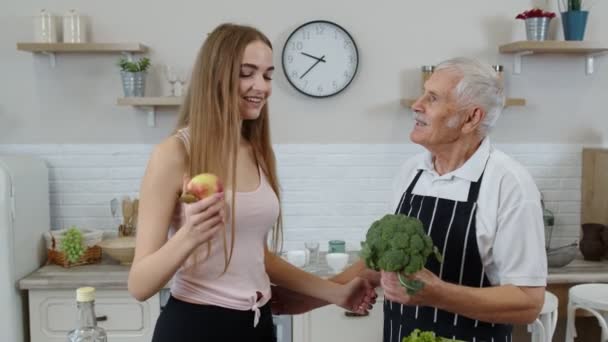 Abuelo mayor con nieta recomendando comer alimentos vegetales crudos. Dieta vegetal — Vídeos de Stock