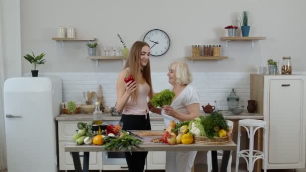 Mujer madura con nieto niña recomendando comer alimentos vegetales crudos. Concepto del día mundial vegano — Vídeo de stock