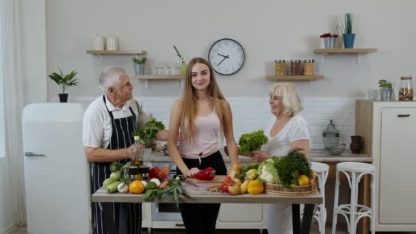 Petite-fille avec grands-parents aînés recommandant de manger des aliments crus aux légumes. Régime alimentaire — Video