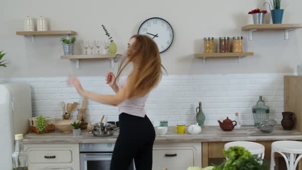 Preciosa chica vegana con el pelo largo bailando y cantando en la cocina moderna. Alimentación vegetal cruda dieta — Vídeos de Stock
