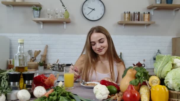 Belle fille mangeant des choux crus sarrasin avec des noix dans la cuisine avec des légumes et des fruits frais — Video