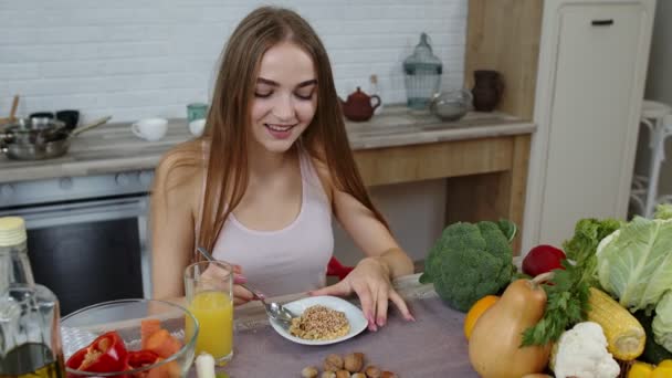 Chica comiendo brotes crudos de trigo sarraceno con nueces en la cocina. Pérdida de peso y dieta. Estilo de vida saludable — Vídeos de Stock