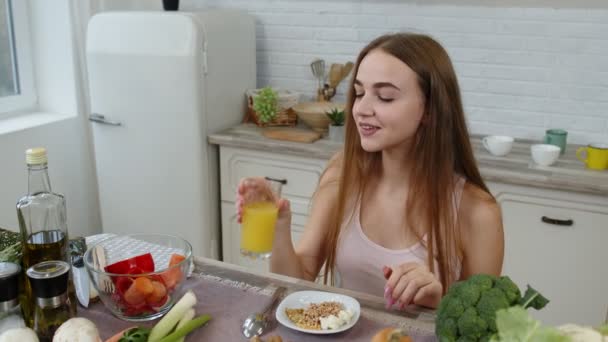 Mädchen essen rohe Sprossen Buchweizen mit Nüssen, trinken Orangensaft in der Küche. Gewichtsverlust und Ernährung — Stockvideo