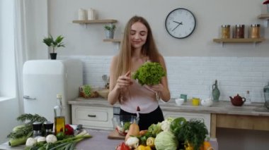 Mutlu kız dans ediyor, eğleniyor ve çiğ sebzelerle salata pişiriyor. Marul parçaları atıyorlar.