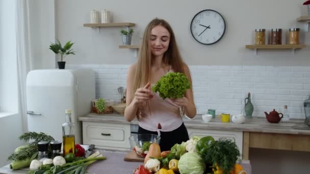Feliz chica bailando, divirtiéndose y cocinando ensalada con verduras crudas. Lanzar trozos de lechuga — Vídeos de Stock