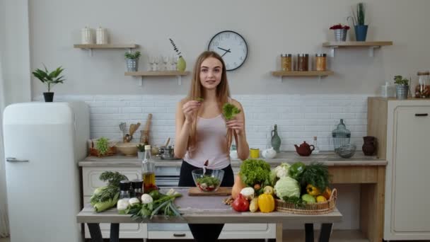 Meisje gooit stukjes sla op het bord, vertelt het recept. Kooksalade met rauwe groenten — Stockvideo