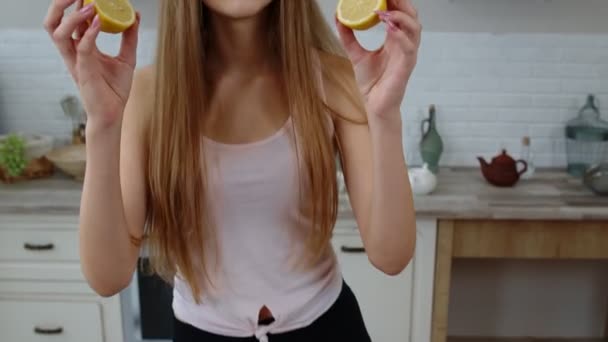 Radostná mladá dívka vegan drží čerstvé půlky citronu na očích a blbne kolem, dělá legrační obličeje — Stock video