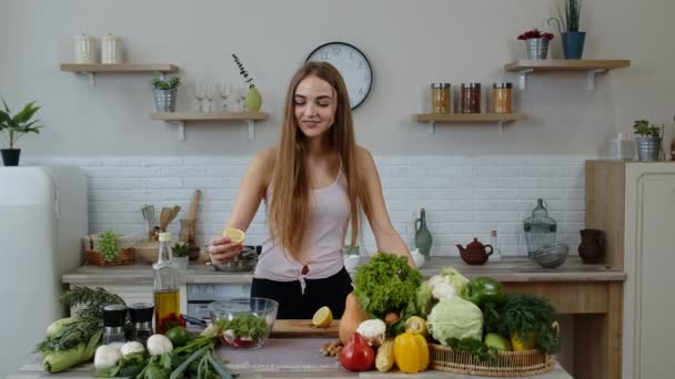 厨房里的一个女孩在沙拉里加柠檬汁和生菜。体重减轻和饮食概念 — 图库视频影像