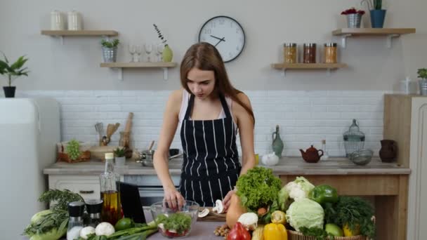 Ensalada de cocina chica vegana con verduras crudas mientras busca en la tableta digital para la receta en línea — Vídeo de stock