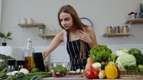 Mujer vegana en busca de receta culinaria en línea en la tableta digital. Ensalada de cocina con verduras crudas — Vídeo de stock