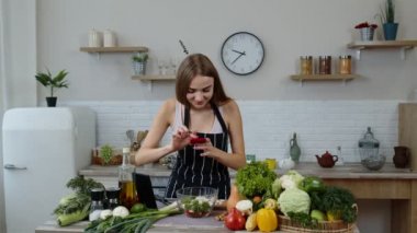 Vegan blogcu kız fotoğraf çekiyor ve sosyal medya için mutfaktaki akıllı telefondan selfie çekiyor.