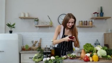 Blogcu kadın yemek hazırlıyor, sosyal hesapları veya video hikayeleri için telefonla fotoğraf çekiyor.