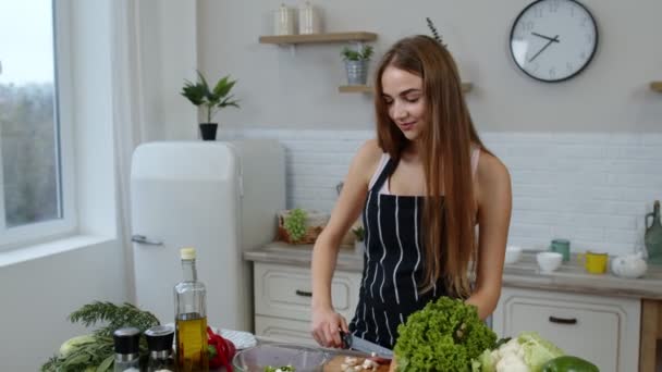 Veganistisch meisje koken salade met rauwe groenten terwijl op zoek op mobiele telefoon voor online recept — Stockvideo