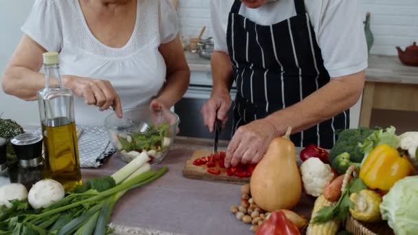 Mutfaktaki yaşlı büyükanne ve büyükbaba. Yaşlı kadın ve erkek taze sebzeli salata pişiriyorlar. — Stok video