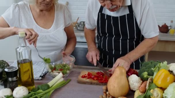 Веганская бабушка и дедушка готовят салат со свежими овощами на кухне дома — стоковое видео