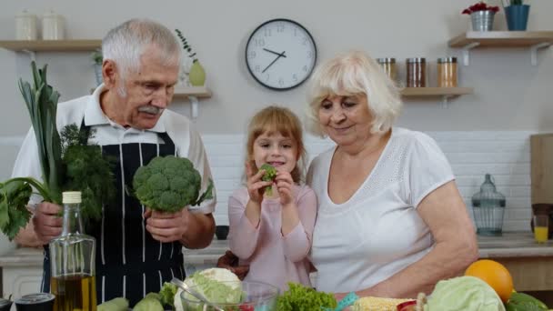 Wnuczka ze starszymi dziadkami polecająca jedzenie surowych warzyw. Dieta żywieniowa — Wideo stockowe