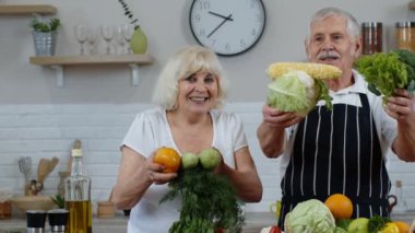 Kıdemli erkek ve kadın çiğ sebze yemeyi öneriyorlar. Mutfakta olgun büyükanne ve büyükbaba çifti