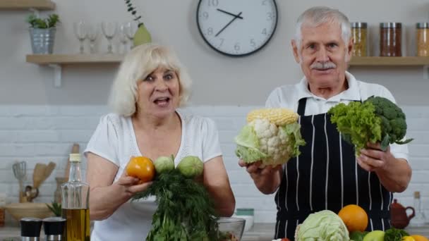 Abuelos mayores pareja en la cocina. Hombre y mujer maduros recomiendan comer alimentos vegetales crudos — Vídeos de Stock