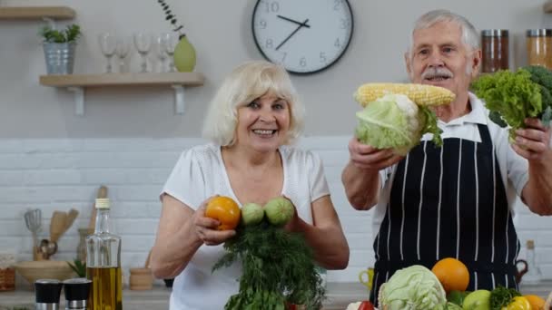 Hombre y mujer mayores recomiendan comer alimentos vegetales crudos. Maduro abuelos pareja en cocina — Vídeos de Stock