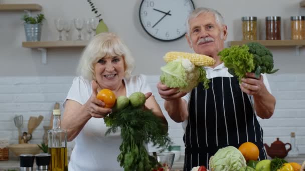 Abuelos mayores pareja en la cocina. Hombre y mujer maduros recomiendan comer alimentos vegetales crudos — Vídeo de stock