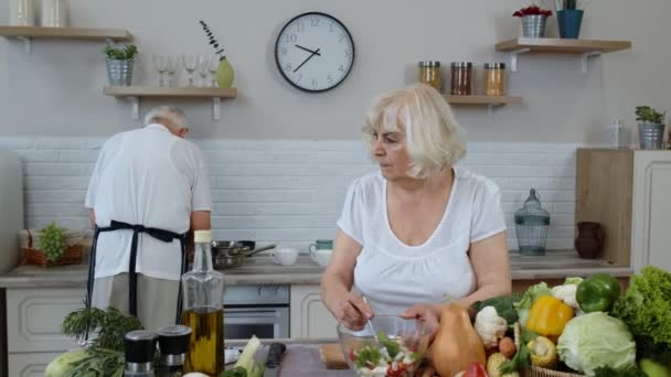 Senior vegán nagymama és nagyapa főzés saláta friss zöldségekkel a konyhában otthon — Stock videók