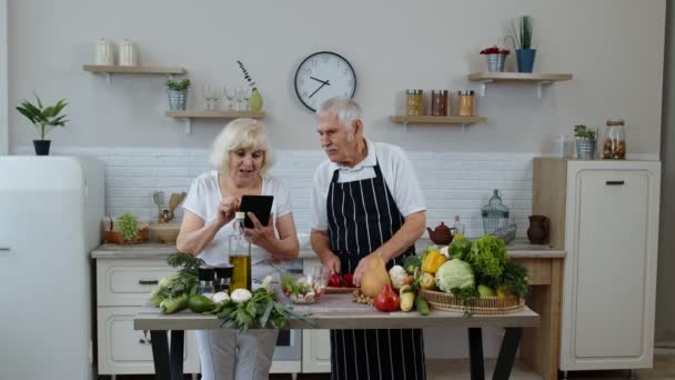 Vejetaryen büyük anne ve büyük baba dijital tablette yemek tarifi arıyor, salata pişiriyorlar. — Stok video