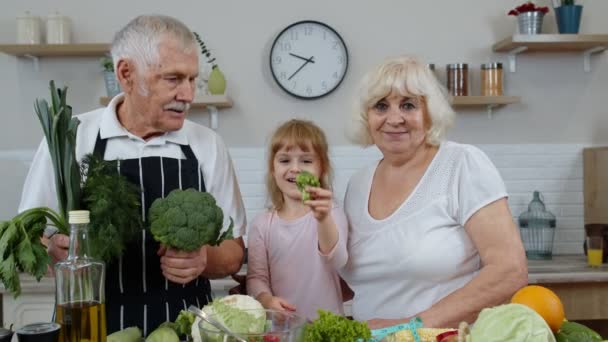 Fille avec un homme et une femme mûrs recommandant de manger des aliments crus aux légumes. Alimentation saine — Video