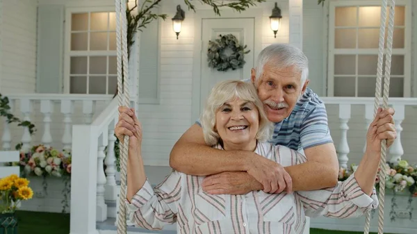 Pareja de ancianos juntos en el patio delantero en casa. Hombre balanceándose mujer. Familia jubilada madura feliz — Foto de Stock