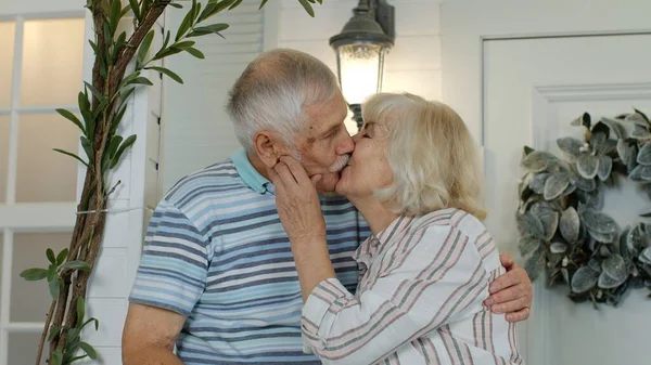 Старшая пара муж и жена обнимаются и целуются дома на крыльце. Счастливая семья — стоковое фото