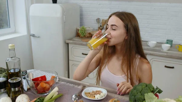 Girl eating raw sprouts buckwheat with nuts, drinking orange juice in kitchen. Weight loss and diet