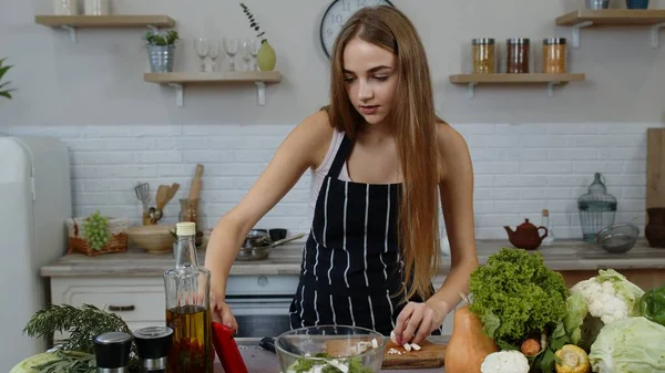 Vegan ragazza cottura insalata con verdure crude mentre cerca sul telefono cellulare per la ricetta online — Foto Stock