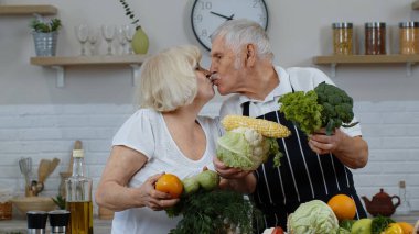 Senior man and woman recommending eating raw vegetable food. Mature grandparents couple in kitchen clipart