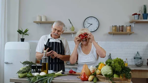 ビーガンシニア祖父母は、デジタルタブレット上でオンライン料理レシピを探しています,調理サラダ — ストック写真