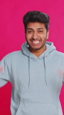 Komik şakacı Hintli adam aptalca yüz ifadeleri yapıyor, suratını buruşturuyor, dalga geçiyor, dil gösteriyor, aptalca bir ifade takınıyor. Komedyen Arap adam pembe arka planda izole edilmiş. İnsan yaşam tarzları