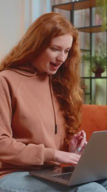 Laptop kullanan Kafkasyalı genç kadın, iyi haberler aldı. Ani zaferle şok oldu. Piyango ikramiyesini evde kazandı. Netbook 'u olan neşeli yetişkin bayan oturma odasında kanepede oturuyor..