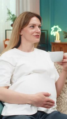 Hamile orta yaşlı bir kadın elinde bir fincan kafeinsiz kahve tutuyor buhar yükselişini seyrediyor sakin kafayla bakıyor. Kanepedeki beyaz kız huzur dolu moladan zevk alıyor aroma bebek yolculuğunu yansıtıyor kendini güvende hissediyor.