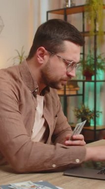 Planlama bütçesi. Zengin, mutlu bir işadamı, evdeki faturaları hesaplamak için dizüstü bilgisayarla dolar sayıyor. Kafkasyalı adam planlı tatil hediyeleri için maaş kazancından memnun..