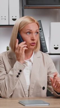 Olgun bir iş kadını cep telefonuyla müşteriye cevap veriyor. Akıllı telefon kullanıyor. Sohbet. Kafkasyalı orta yaşlı kadın uzaktan kumandalı internet işinde çalışıyor, ofis masasında konuşuyor..