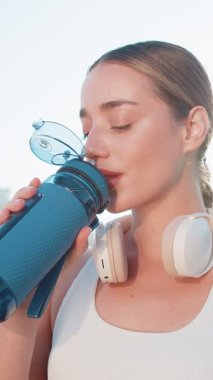 Sporcu formda koşucu kız antrenmandan sonra biberondan su içiyor. Sabah parkta kardiyo çalışacaksın. Genç zayıf kadın koşucu sağlıklı yaşam tarzının tadını çıkarıyor. Aktif sporcu kadın aktiviteleri.