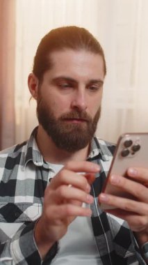 Genç adam evde oturmuş, hızlı bir şekilde telefondaki metni giriyor ve çevrimiçi market yerinde mükemmel bir indirim istiyor. Kanepede oturan adam inanılmaz bir ifade takınıyor ve çok faydalı bir teklif sunuyor.