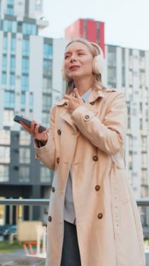 Kablosuz kulaklıklarıyla dans eden, açık havada dans eden enerjik disko müziği dinleyen mutlu, rahat, olgun bir iş kadını. Şehir merkezindeki caddede duran palto giymiş aşırı neşeli bir kız. İş adamları.