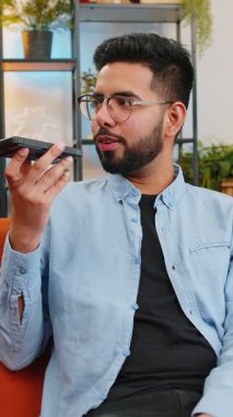 Neşeli Hintli adam gezici hoparlörlerden hoşlanıyor dedikodular, dedikodular, iyi haberler koltukta oturuyor. Modern ev odasındaki arkadaşlarıyla telefon konuşması yapan mutlu, heyecanlı Arap adam..